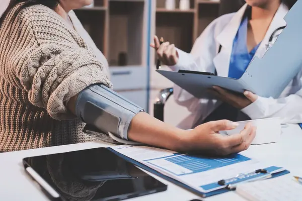 Steteskopla sfenometre kullanan bir doktor hastanede kan basıncını ölçüyor..