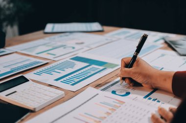 Bir grup iş adamı, analitik plan toplantısında beyin fırtınası yaparak grafikten elde edilen rakamları hesaplıyor. Finansal büyüme tablosu. Pazarlama. İş başarısı istatistikleri kavramı.