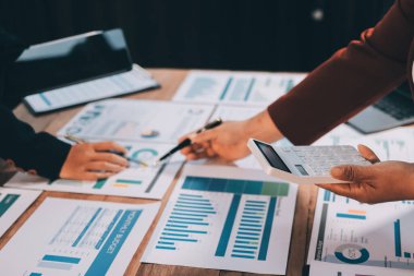 Bir grup iş adamı, analitik plan toplantısında beyin fırtınası yaparak grafikten elde edilen rakamları hesaplıyor. Finansal büyüme tablosu. Pazarlama. İş başarısı istatistikleri kavramı.