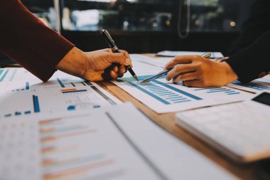 Bir grup iş adamı, analitik plan toplantısında beyin fırtınası yaparak grafikten elde edilen rakamları hesaplıyor. Finansal büyüme tablosu. Pazarlama. İş başarısı istatistikleri kavramı.