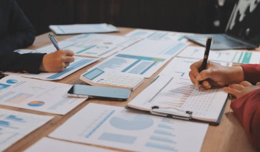 Bir grup iş adamı, analitik plan toplantısında beyin fırtınası yaparak grafikten elde edilen rakamları hesaplıyor. Finansal büyüme tablosu. Pazarlama. İş başarısı istatistikleri kavramı.