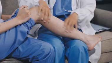 Kadın doktor hasta bacağını muayenehanede tutuyor..