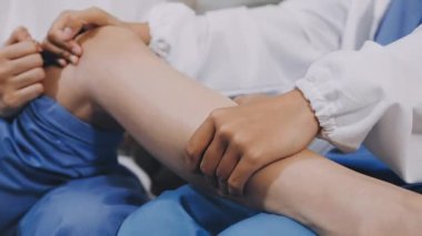 Tıbbi eldivenli doktor, hastanın dizini muayene ediyor.