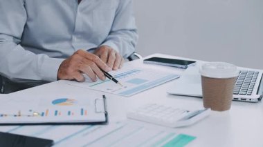 Ofisteki masada doküman ve hesap makinesiyle çalışan bir iş adamı..