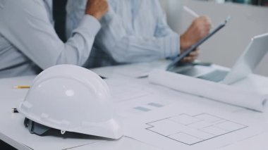 Masada dizüstü bilgisayar ve kaskla çalışan mühendis.