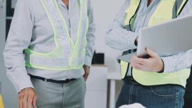 Modern bina içinde elinde beyaz gömlek ve güvenlik yeleği olan mühendis ya da mühendis elinde taslak tutuyordu. mühendislik ve inşaat kavramı.