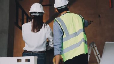 İnşaat alanında çalışan genç Asyalı kadın mühendis. Dizüstü bilgisayarları ve bina planları var.