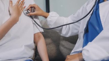 Genç Asyalı doktor steteskop tutuyor ve kalp atışlarını kontrol ediyor. Sağlık ve Tıp Konsepti