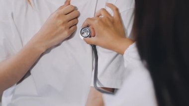 Genç bir kadının arka planında steteskop tutan doktor..