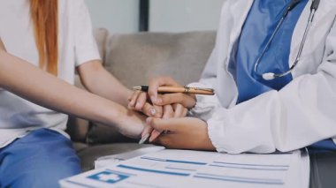 Genç bayan doktor hastanede el ele tutuşuyor.