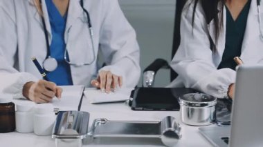 Hastanedeki masada dizüstü bilgisayarla çalışan bir grup doktor..