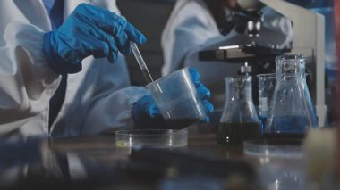 Laboratuvarda çalışan koruyucu eldivenli bilim adamlarının yakın çekim görüntüleri.