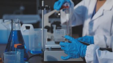 Laboratuvarda mikroskop ve test tüpleri olan bilim adamı.