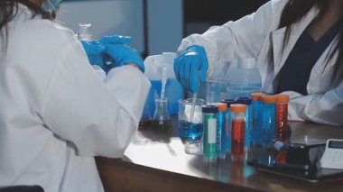 Koruyucu eldivenli ve koruyucu gözlüklü kadın laboratuvar asistanı.