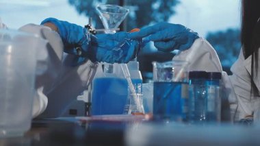 Koruyucu eldivenli ve koruyucu maskeli bilim adamı laboratuarda kimyasal deney yapıyor. Coronavirus konsepti