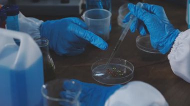 Tıbbi eldivenli bir elin mavi sıvıyla test tüpünü tutarken yakın plan görüntüsü..