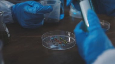 Koruyucu eldivenli bir bilim adamı, üzerinde bir örnek olan bir test tüpü tutuyor.