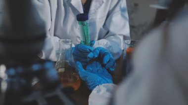 Yakın plan - koruyucu eldivenli bilim adamlarının laboratuarda numunelerle test tüpleri tutması.