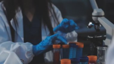 Laboratuvar önlüklü bir kadın bilim adamının elinde sıvı tutan bir tüp..