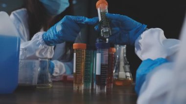 Bilim adamı bardağı sıvıyla tutuyor.