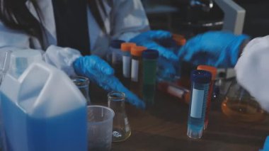 Kadın bilim adamı laboratuvarda kimyasal sıvıyla dolu bir tüp tutuyor.