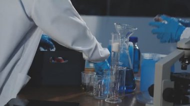 Yakın plan - erkek bilim adamının laboratuarda matarayı tutuşu.