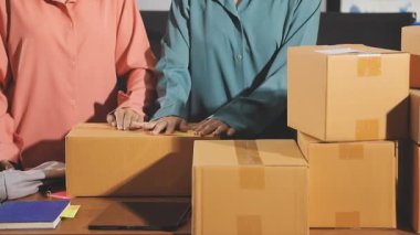 İş ekibi laptopta çalışıyor ve karton kutuları ofise teslim etmek için paketliyor..