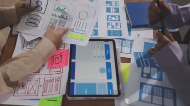 Genç iş kadını tablet kullanıyor ve iş planlarını ofisteki meslektaşlarıyla tartışıyor.