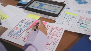 Tasarımcı ofiste iş planıyla birlikte tablet üzerinde çalışıyor