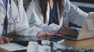 Modern klinikteki masada çalışan dizüstü bilgisayarı ve steteskopu olan bir doktor..