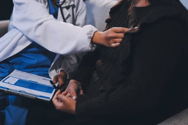 Ev bakımı hemşiresi ve yaşlılar kardiyoloji sağlık hizmetleri. Genç İspanyol kadın doktor hemşirenin yakın çekimleri sırasında steteskop kullanarak olgun beyaz hasta kalp atışlarını kontrol et.