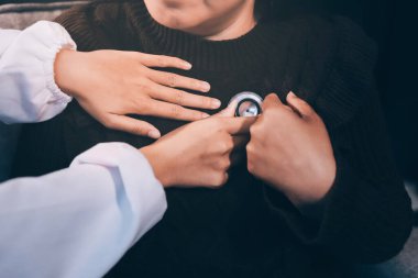 Ev bakımı hemşiresi ve yaşlılar kardiyoloji sağlık hizmetleri. Genç İspanyol kadın doktor hemşirenin yakın çekimleri sırasında steteskop kullanarak olgun beyaz hasta kalp atışlarını kontrol et.