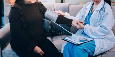 Kan basıncı monitörü ve steteskop kullanan doktor kolundaki kan basıncını ölçmek için hastanedeki bir hastaya, sağlık hizmetlerine ve tıbbi konsepte bakıyor.