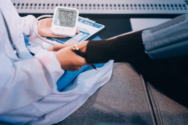 Kan basıncı monitörü ve steteskop kullanan doktor kolundaki kan basıncını ölçmek için hastanedeki bir hastaya, sağlık hizmetlerine ve tıbbi konsepte bakıyor.