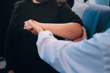 Ortopedi doktoru klinikte bileği ağrıyan bir hastayı muayene ediyor. Fizyoterapist bilek kemiğine bastırarak hastanın bileğini kontrol eder..