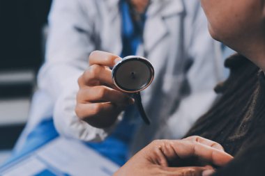 Ev bakımı hemşiresi ve yaşlılar kardiyoloji sağlık hizmetleri. Genç İspanyol kadın doktor hemşirenin yakın çekimleri sırasında steteskop kullanarak olgun beyaz hasta kalp atışlarını kontrol et.