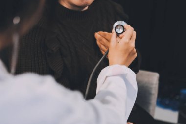 Ev bakımı hemşiresi ve yaşlılar kardiyoloji sağlık hizmetleri. Genç İspanyol kadın doktor hemşirenin yakın çekimleri sırasında steteskop kullanarak olgun beyaz hasta kalp atışlarını kontrol et.