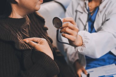 Ev bakımı hemşiresi ve yaşlılar kardiyoloji sağlık hizmetleri. Genç İspanyol kadın doktor hemşirenin yakın çekimleri sırasında steteskop kullanarak olgun beyaz hasta kalp atışlarını kontrol et.