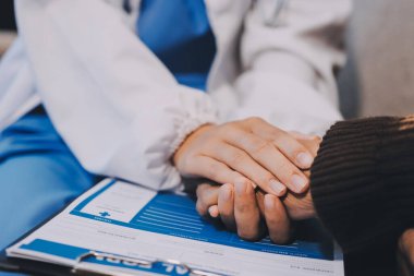 Doktor hastayı kontrol etmeye geldi ve cesaretlendirmek için elini sıktı. Hastanede tedavi edilenleri ve hastaları teselli etmek..