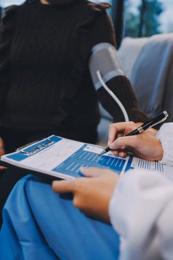 Kan basıncı monitörü ve steteskop kullanan doktor kolundaki kan basıncını ölçmek için hastanedeki bir hastaya, sağlık hizmetlerine ve tıbbi konsepte bakıyor.