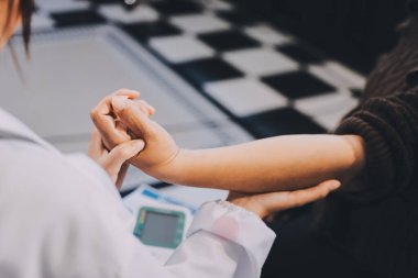 Ortopedi doktoru klinikte bileği ağrıyan bir hastayı muayene ediyor. Fizyoterapist bilek kemiğine bastırarak hastanın bileğini kontrol eder..
