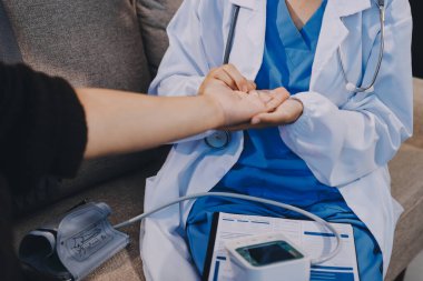 Ortopedi doktoru klinikte bileği ağrıyan bir hastayı muayene ediyor. Fizyoterapist bilek kemiğine bastırarak hastanın bileğini kontrol eder..