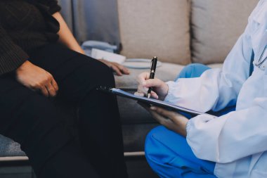 Genç doktor kıdemli hastanın bacağını muayene ediyor.