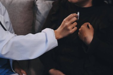 Ev bakımı hemşiresi ve yaşlılar kardiyoloji sağlık hizmetleri. Genç İspanyol kadın doktor hemşirenin yakın çekimleri sırasında steteskop kullanarak olgun beyaz hasta kalp atışlarını kontrol et.