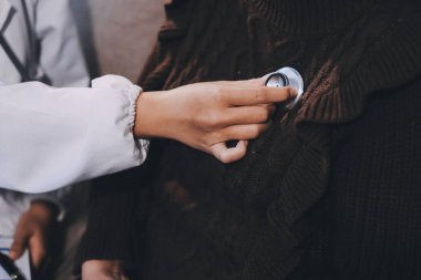 Ev bakımı hemşiresi ve yaşlılar kardiyoloji sağlık hizmetleri. Genç İspanyol kadın doktor hemşirenin yakın çekimleri sırasında steteskop kullanarak olgun beyaz hasta kalp atışlarını kontrol et.