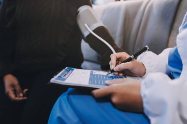 Kan basıncı monitörü ve steteskop kullanan doktor kolundaki kan basıncını ölçmek için hastanedeki bir hastaya, sağlık hizmetlerine ve tıbbi konsepte bakıyor.