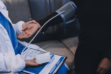 Kan basıncı monitörü ve steteskop kullanan doktor kolundaki kan basıncını ölçmek için hastanedeki bir hastaya, sağlık hizmetlerine ve tıbbi konsepte bakıyor.