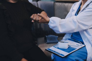 Ortopedi doktoru klinikte bileği ağrıyan bir hastayı muayene ediyor. Fizyoterapist bilek kemiğine bastırarak hastanın bileğini kontrol eder..