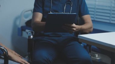 Üniformalı doktor ve hasta hastane ofisinde oturuyor.