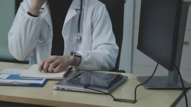 Doktor ofiste bilgisayarla çalışıyor.